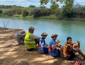Students sitting on the edge of the Daly River.