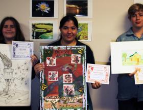 College art students holding their artwork and certificates.